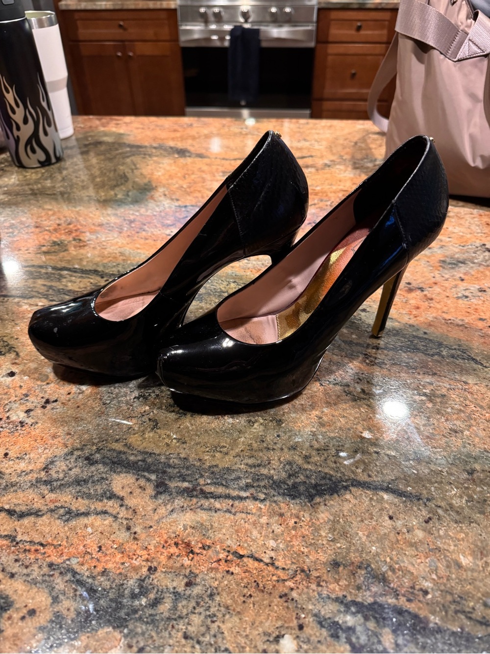 Ted Baker London black patent leather pumps with snakeskin heel detail.